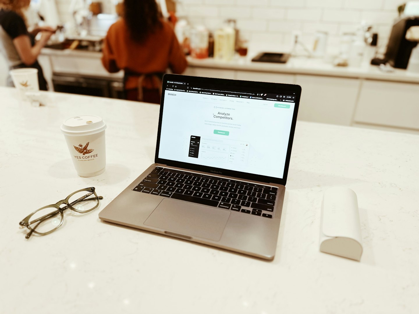 Laptop with analytics dashboard and coffee on a white tabletop.